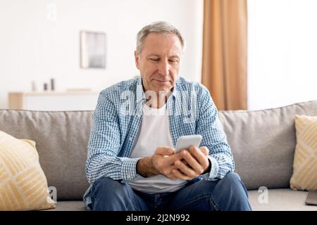 Portrait of smiling mature man using smartphone at home Stock Photo