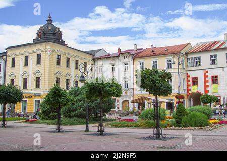 Banska Bystrica, Slovakia - August 17, 2021: view of SNP Square - colorful historic buildings, blooming flowers, green trees and people walking around Stock Photo