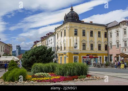 Banska Bystrica, Slovakia - August 17, 2021: view of SNP Square - colorful historic buildings, blooming flowers, green trees and people walking around Stock Photo