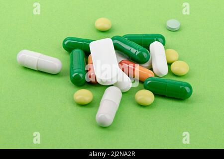 Heap of colorful pills and capsules for medical treatment on green background Stock Photo