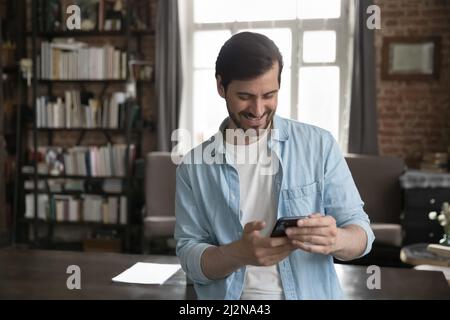 Happy joyful millennial business man using online app on smartphone Stock Photo