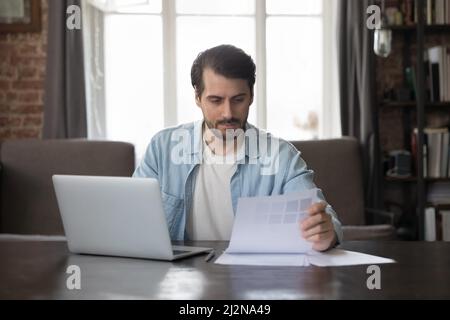 Focused professional interior designer reviewing paper with samples of colors Stock Photo