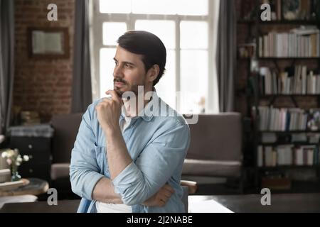 Pensive millennial entrepreneur touching chin in deep thoughts Stock Photo