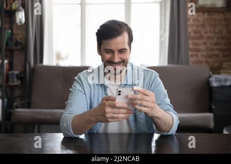 Happy cheerful freelance business professional using online app on smartphone Stock Photo