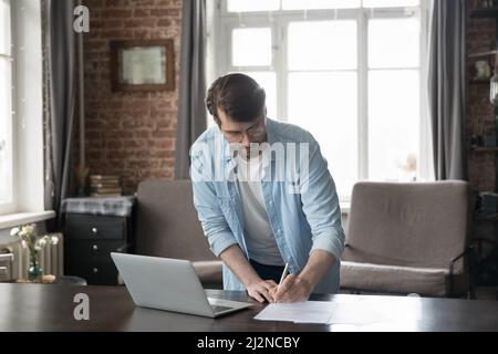 Busy focused business man signing paper contract, checking documents Stock Photo