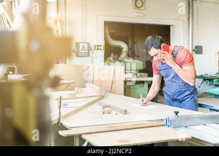 Carpenter talking on phone while taking notes Stock Photo
