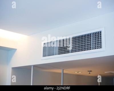 Air conditioning wall mounted ventilation system on ceiling in the white hotel room. Hotel room air ventilation grill on the wall. Stock Photo