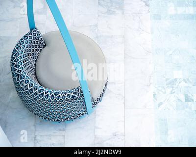 Top view of modern blue round rattan seat on the marble tiles floor near the pool with copy space. Empty modern furniture with circle shape of cozy pa Stock Photo