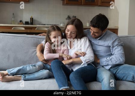 Happy parents, mom and dad cuddling, tickling little daughter kid Stock Photo