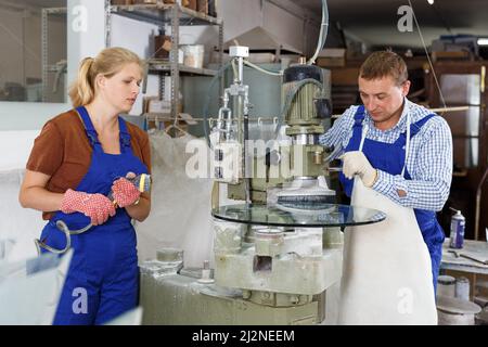 Man working on curved glass beveling machine Stock Photo