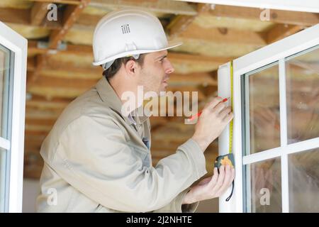 man measuring window prior to installation Stock Photo