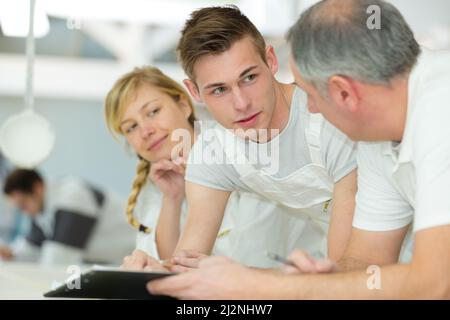 apprentice on jumper suits conversing with teacher Stock Photo