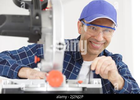 happy workman using circular saw in workshop Stock Photo