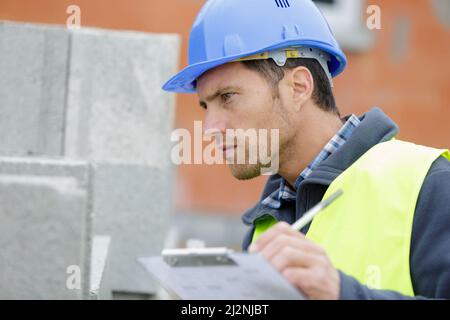 handsome man in hardhat checking block Stock Photo