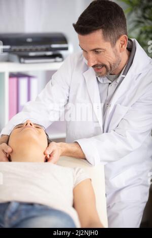physiotherapist or a chiropractor adjusting patients neck Stock Photo