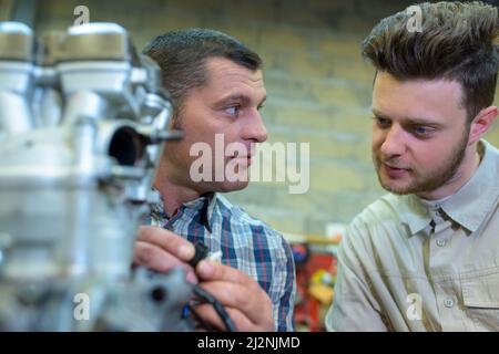mechanic in onversation with his apprentice Stock Photo