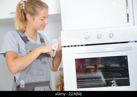 young woman is installing a brand new oven in kitchen Stock Photo