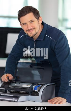 hardware repairman repairing broken printer fax machine Stock Photo