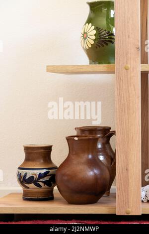 Different ceramic pottery vases on shelves, interior design Stock Photo