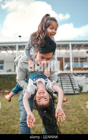 Our dad is so much fun. Shot of a father bonding with his two young daughters outside. Stock Photo