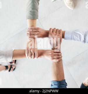 Developing a good work ethic is key. Cropped shot of a group of businesspeople linking their arms in solidarity at work. Stock Photo
