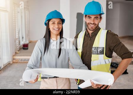 Building the house weve always dreamt of. Shot of two young architects looking at building plans on site. Stock Photo