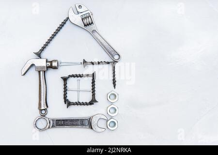 House shape made from a miniature hammer, wrenches, screws, nails and nuts on a concrete background. Do it yourself house repair and maintenance conce Stock Photo