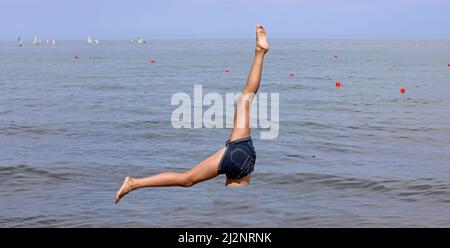 two legs of the athlete in the water of the sea during a gymnastic exercise in apnea in summer Stock Photo
