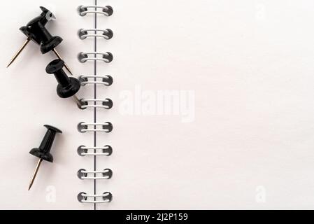 Black pins for notes or office paper on a notebook. Place for an inscription. Stationery Stock Photo