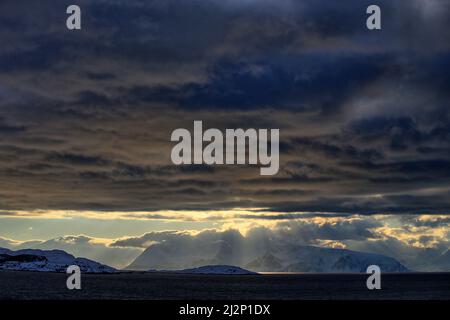 Von Alta nach Sortland -Die Abendsonne bestrahlt die dunkle Wolkendecke von unten und taucht die Wolken in magisches Licht Stock Photo