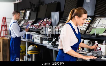 Smiling female car painter preparing paints for paintwork in modern auto repair shop Stock Photo