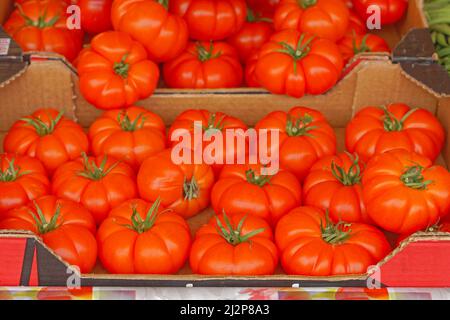 Big French tomatoes in crates at farmers market Stock Photo