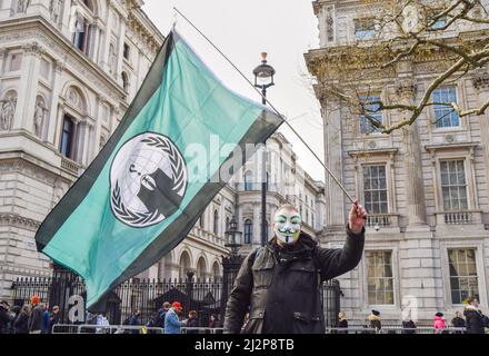 London, UK. 02nd Apr, 2022. A protester wearing a mask holds a flag from 'hacktivist' group Anonymous during the cost of living demonstration. Hundreds of people gathered outside Downing Street in protest against the rise in energy costs, the cost of living crisis and the Tory Government. (Photo by Vuk Valcic/SOPA Images/Sipa USA) Credit: Sipa USA/Alamy Live News Stock Photo