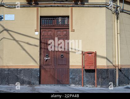 Old brown door with iron knockers with a post box on the side Stock Photo