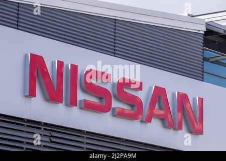 Helsinki / Finland - APRIL 3, 2022: Closeup of a signpost with Nissan logo against a bright blue sky Stock Photo