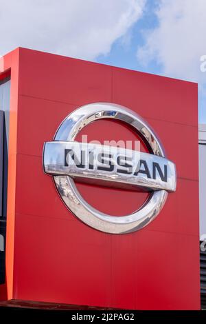 Helsinki / Finland - APRIL 3, 2022: Closeup of a signpost with Nissan logo against a bright blue sky Stock Photo