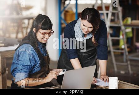 Tell me what you think. Cropped shot of two attractive young creative female artisans working on a laptop in their workshop. Stock Photo