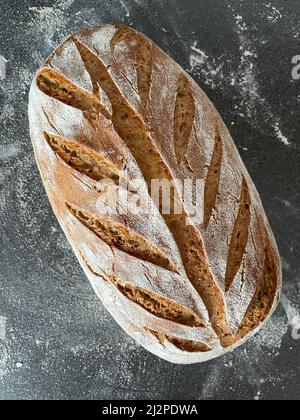 whole grain wheat bread made with sour dough on grey surface with ear pattern in bread crust Stock Photo