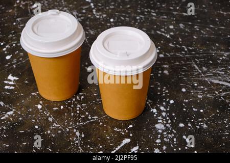 Two paper coffee disposable cups on background dirty floor Stock Photo