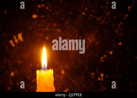 Candle burning brightly against dark wall Stock Photo