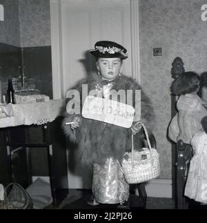 1961, historical, in a shiny dress, fur top, fancy hat, jewellery and shoulder bag, a young girl  standing on a chair, dressed up for her birthday as 'Lady Docker', Stockport, Manchester, England, UK. In post-war British, Lady Docker - born Norah Royce Turner in a flat over a butchers shop in Derby - was a 'personality', a socialite. Through marriage, in particular her third marriage to Sir Bernard Docker, Chairman of the Daimler car company and a director of Midland Bank, she led a colourful, extravagant life for the time, but she never forgot her humble working class roots. Stock Photo