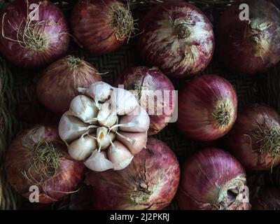 Dry garlic bulb, and red shallot bulbs in a basket for sale at a wet market in Bangkok, Thailand. Top view. Close-up. Stock Photo