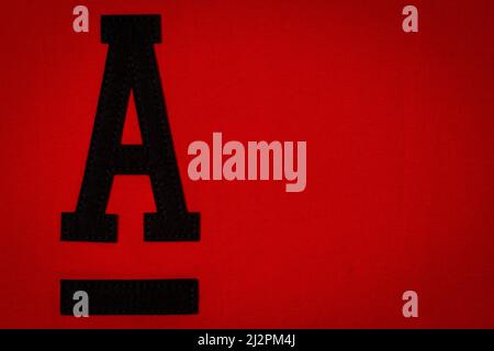 Letter A. Alphabet letter A application and blank label tag made from black material on red fabric background Stock Photo