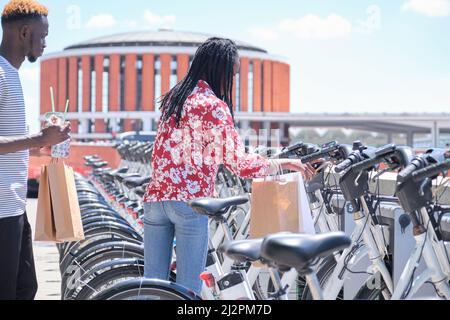 Young african tourists renting a bike at a bicycle rental service machine. Stock Photo