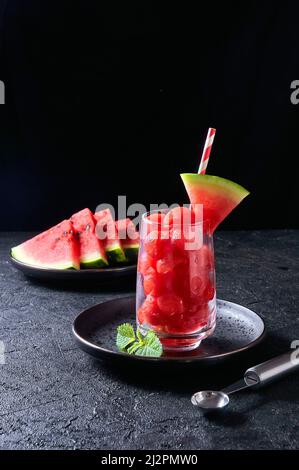 Ripe watermelon noisette balls in glass with mint on dark background. Summer dessert Stock Photo