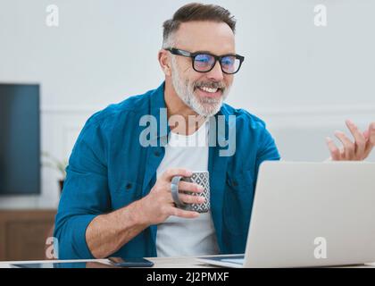 Good news is the order of the day. Shot of a mature businessman working from home using his laptop. Stock Photo
