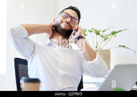 Well.... Shot of a handsome young businessman sitting alone in the office and suffering from neck pain while using technology. Stock Photo