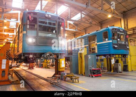 Passenger locomotives of the underground metro raised on jacks with headlights on in the depot, maintenance and replacement of engines and wheelsets, Stock Photo