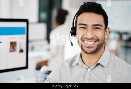 Success is liking yourself. Shot of a young businessman wearing a headset while working in an office. Stock Photo