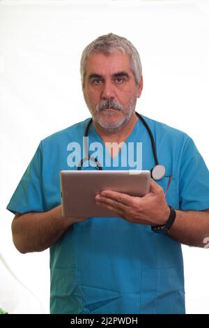 Senior doctor looking at camera with tablet in hand checking patient data. Annual medical check-up. Stock Photo